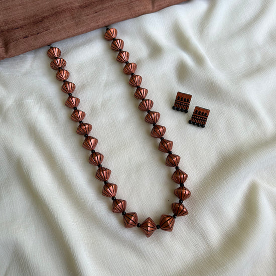 A set of clay copper bead necklaces with adjustable thread, displayed on a white fabric surface.