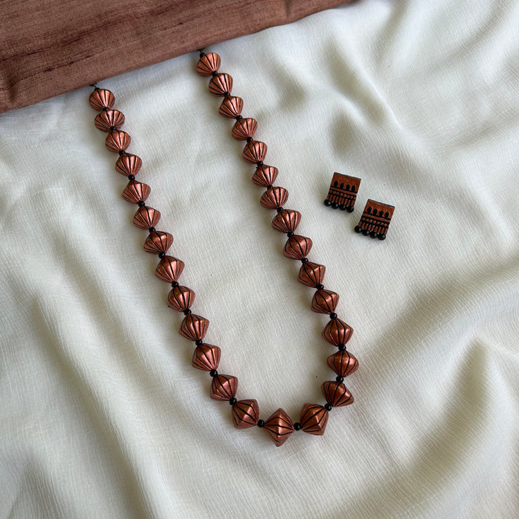 A set of clay copper bead necklaces with adjustable thread, displayed on a white fabric surface.