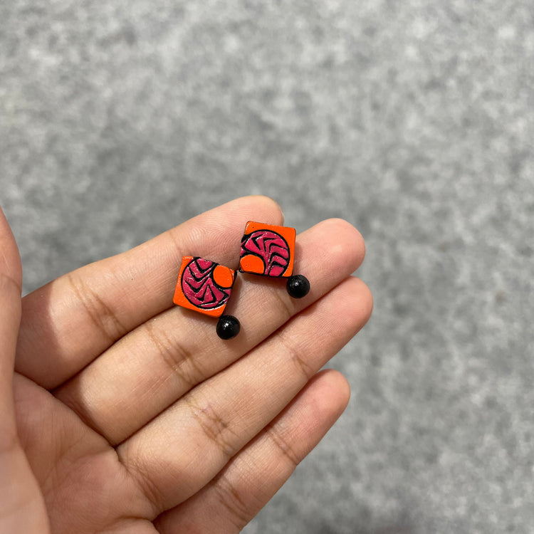Handmade orange tribal terracotta stud earrings with curved arrows.