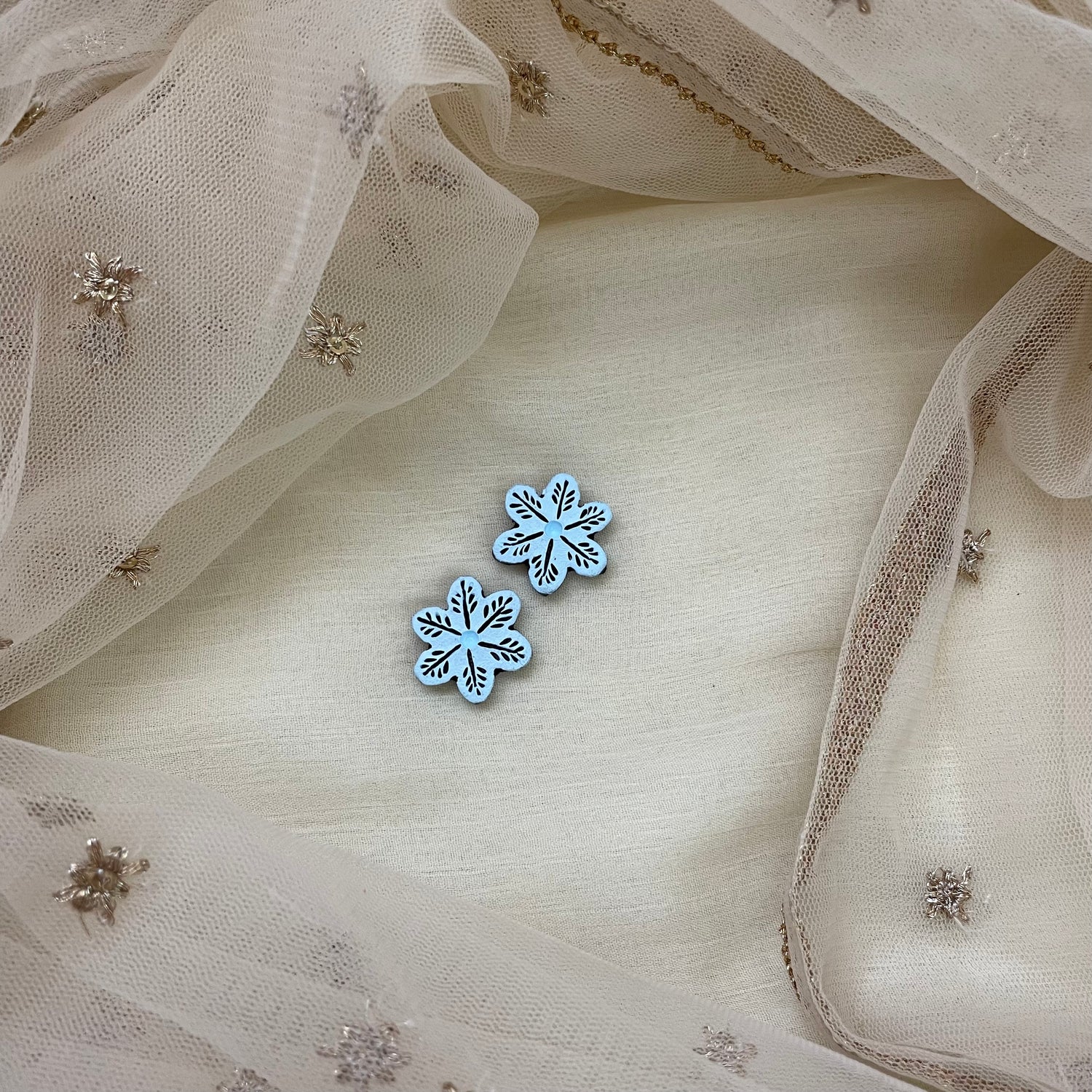 Handmade white flower terracotta clay stud earrings with a black outline.